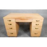 A mid century vintage limed oak pedestal desk with two banks of drawers and central frieze drawer