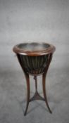 An Edwardian mahogany urn shaped jardiniere stand with brass drop-in liner raised on swept