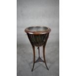 An Edwardian mahogany urn shaped jardiniere stand with brass drop-in liner raised on swept