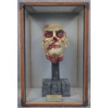 A vintage plastic and plaster painted zombie head on a concrete effect stand housed within a bespoke