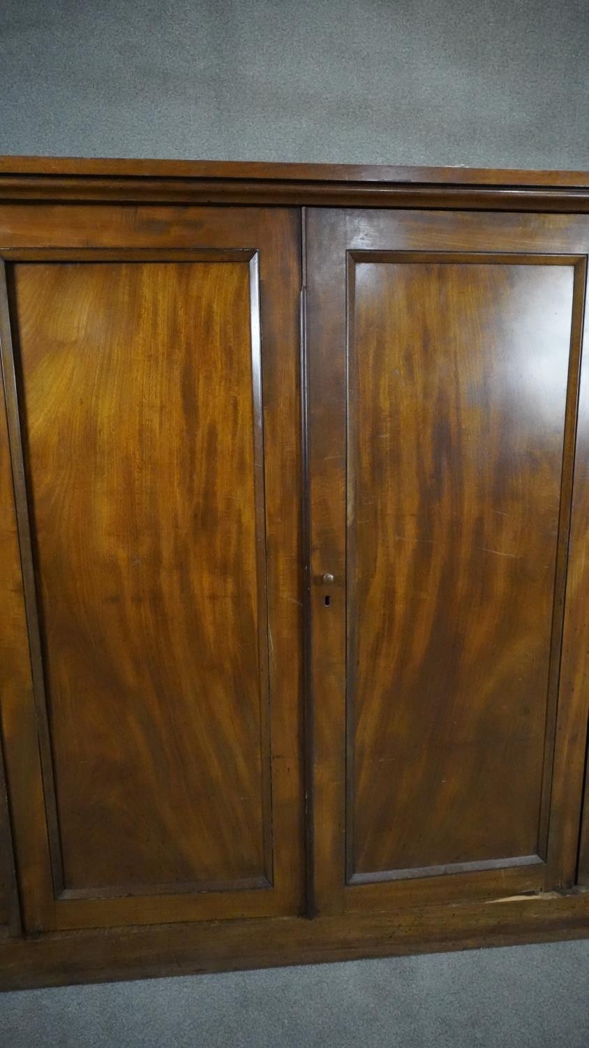 An mid 19th century mahogany linen cupboard with central panel doors flanked by two banks of four - Image 4 of 14