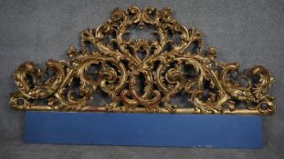 A giltwood Baroque carved panel or head board with profuse foliate, fruit and flowerhead decoration.