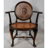 An early 20th century mahogany framed office armchair with caned back and seat on stretchered