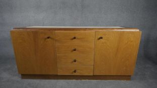 A contemporary teak sideboard with inset marble top above a bank of four central drawers flanked