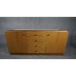 A contemporary teak sideboard with inset marble top above a bank of four central drawers flanked