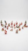 Twenty one vintage hand painted bisque porcelain Christmas cake decorations and two Christmas trees.