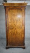 A mid century early Georgian style burr walnut wardrobe with panel door enclosing hanging space on
