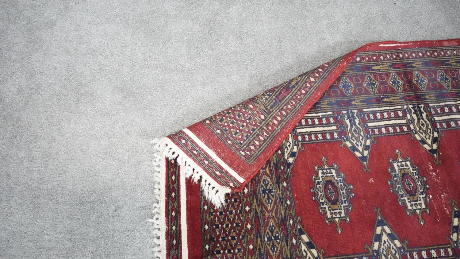 A signed Pakistan Bokhara rug with red ground within a central pendant motif. H.185 W.135 - Image 5 of 5