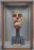 A vintage plastic and plaster painted zombie head on a concrete effect stand housed within a bespoke