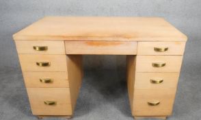 A mid century vintage limed oak pedestal desk with two banks of drawers and central frieze drawer