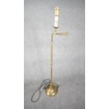 A contemporary brushed brass swing arm height adjustable floor lamp with circular base. Two pin