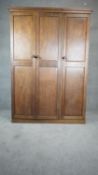 An Arts and Crafts oak compactum wardrobe fitted with panel doors enclosing hanging space and fitted