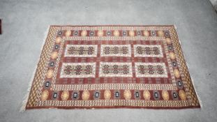 A Pakistan Bokhara rug with mink ground, central column design within a floral border. H.96 W.160