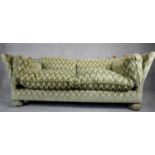 A Knole sofa in cut velour upholstery the drop ends with carved giltwood finials raised on bun feet.