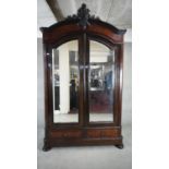 A C.1900 French burr walnut armoire with arched carved pediment above twin shaped and bevelled doors