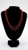 A 14 carat gold and coral long chain necklace comprised of 134 polished barrel shaped coral beads