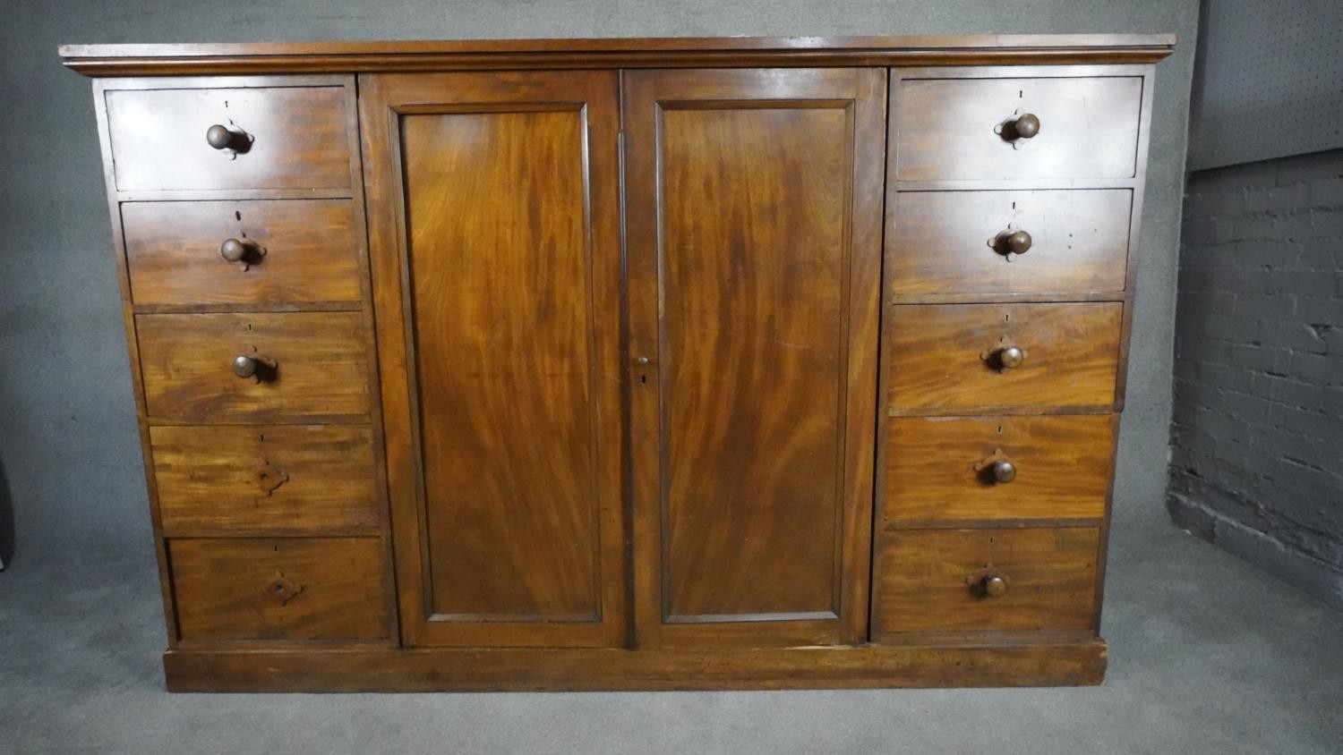 An mid 19th century mahogany linen cupboard with central panel doors flanked by two banks of four