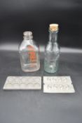 Two vintage milk bottles and two French metal chocolate moulds impressed with maker's marks. H.30