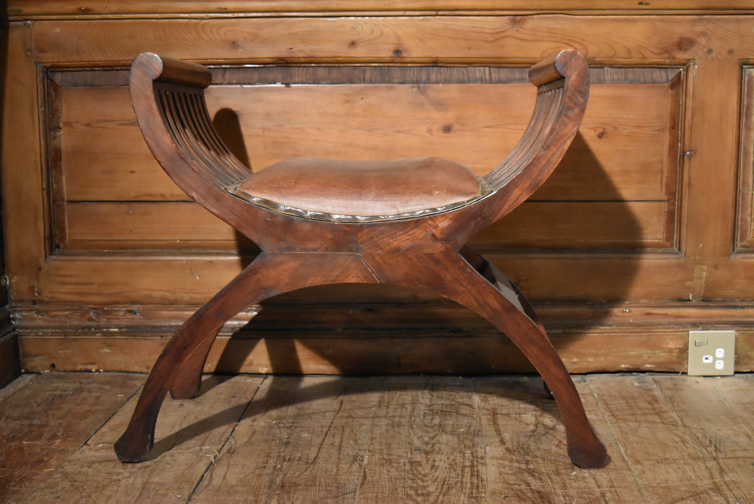 A contemporary teak X framed stool in leather upholstery. H.60 W.56 D.37cm