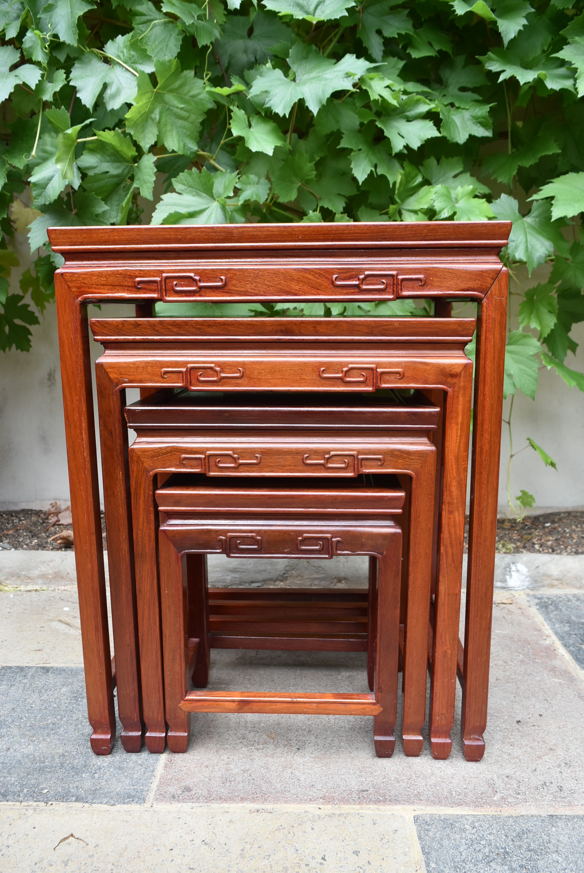 A nest of four Chinese hardwood graduating occasional tables with carved friezes on square