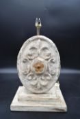 A painted metal table lamp with Fleur de Lys cartouche to one side on stepped distressed painted