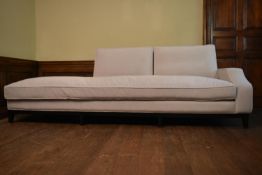 A contemporary chaise longue in piped upholstery and fitted with long squab cushion on square