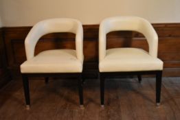 A pair of contemporary hooped back armchairs in piped ivory leather upholstery on ebonised square