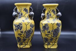 A pair of Chinese porcelain vases with foliate decoration on a yellow background and fixed fruit