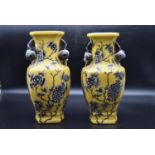 A pair of Chinese porcelain vases with foliate decoration on a yellow background and fixed fruit