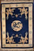 A Chinese rug with dragon medallion and spandrels on a sapphire ground within fawn border with