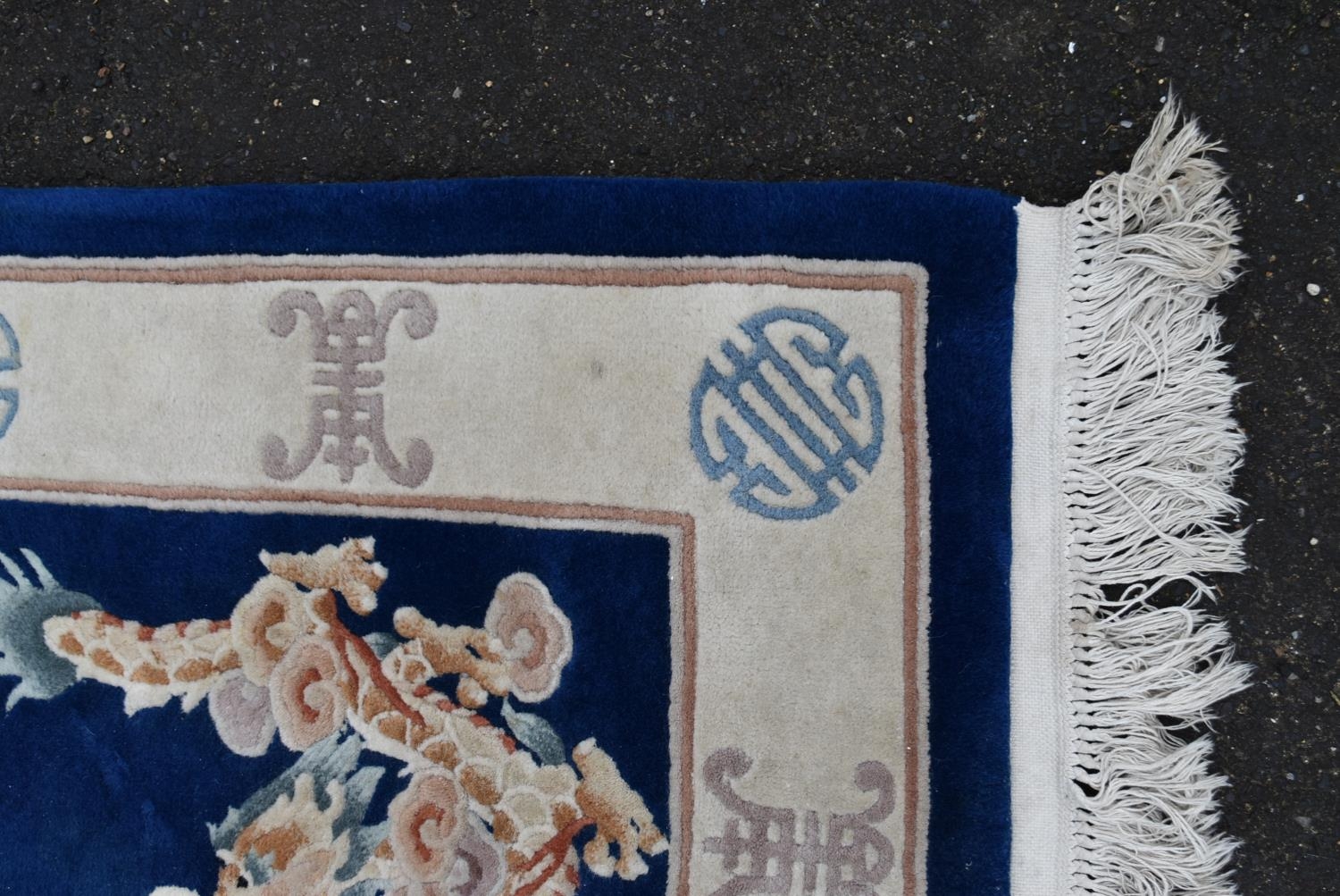 A Chinese rug with central floral medallion and dragon spandrels on a sapphire field surrounded with - Image 2 of 4