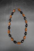 A vintage faux amber necklace comprising of amber and black faceted beads. L.43cm