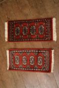 Two Pakistani Bokhara rugs on rust ground. H.70 W.30cm (2)