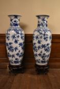 A pair of 20th century Chinese style blue and white floral design vases on carved hardwood stands.