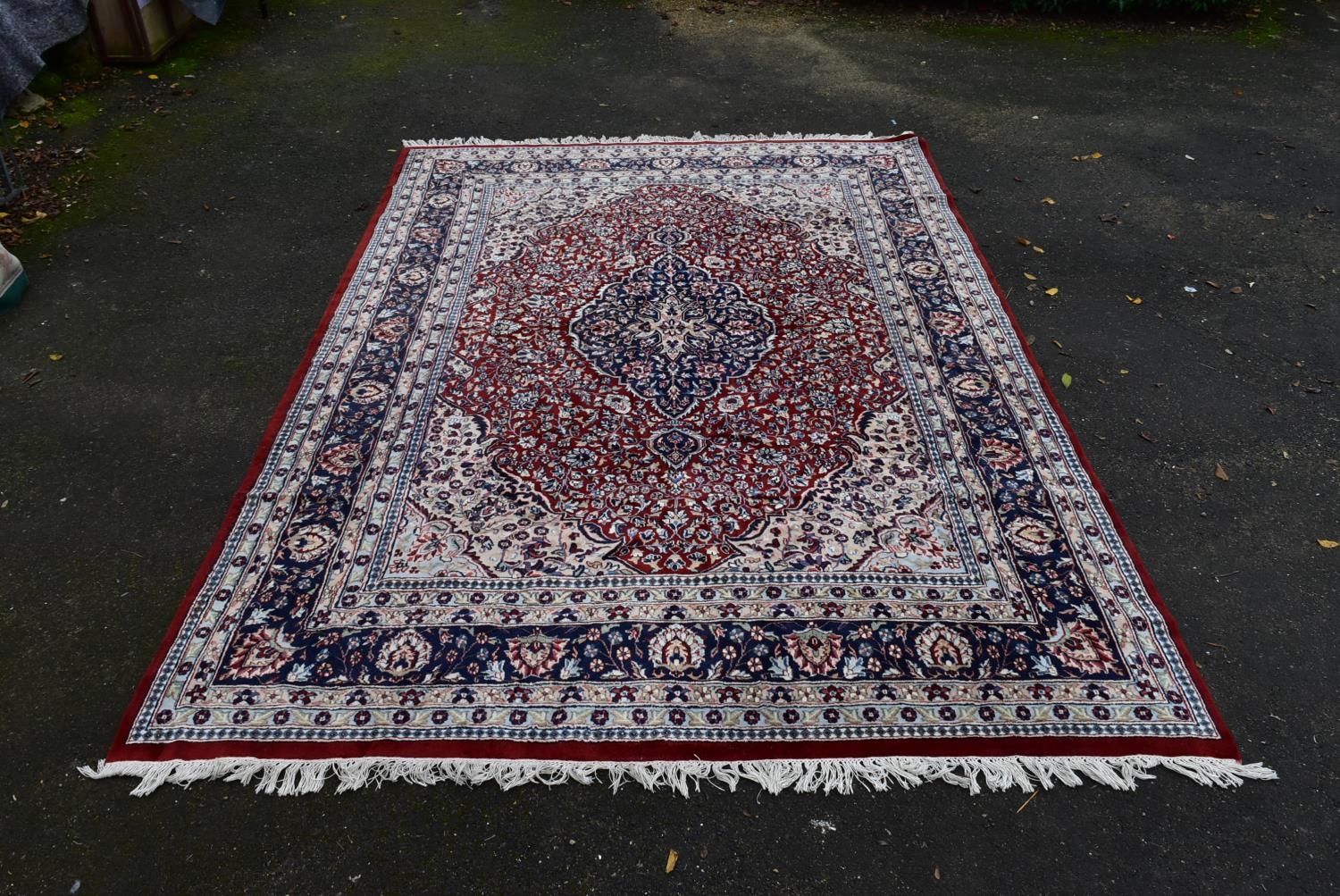 A Persian Keshan carpet with floral central medallion on burgundy ground within foliate spandrels