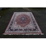 A Persian Keshan carpet with floral central medallion on burgundy ground within foliate spandrels