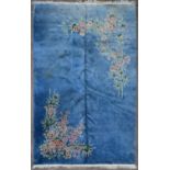 A large Chinese deep pile woollen rug with profuse floral sprays on a sapphire ground. L.430 W.303cm