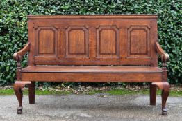 A Georgian oak and mahogany crossbanded panel back settle with scroll arms and floral upholstered