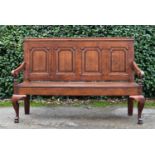 A Georgian oak and mahogany crossbanded panel back settle with scroll arms and floral upholstered