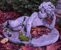 A composite garden statue of a young boy laying on his side. H.40cm