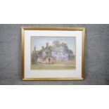 A framed and glazed watercolour on paper of a country cottage covered in Wisteria. Signed E.J.