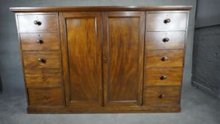 An mid 19th century mahogany linen cupboard with central panel doors flanked by two banks of four