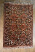 A Shirvan rug with repeating floral lozenge medallions on a madder ground within flowerhead borders.