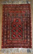 An Eastern prayer rug with repeating gul motifs on burgundy ground with stylised floral multi