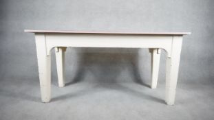 A distressed painted farmhouse dining table on square tapering supports. H.76 W.153 D.61