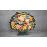 A cut out wooden screen with easel back, with decoupage flowers in a painted urn. Signed A.