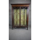 An Edwardian mahogany and satinwood inlaid display case with circular pane astragal glazed doors