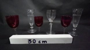 Three Victorian cranberry glass wine glasses along with a pair of antique petal facet liqueur