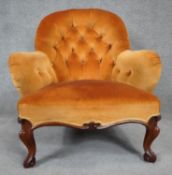 A Victorian mahogany framed armchair in deep buttoned upholstery on carved cabriole supports. H.85cm