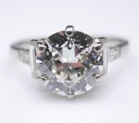 An 18 carat white gold diamond flanked solitaire ring. Set to centre with a round old cut diamond in